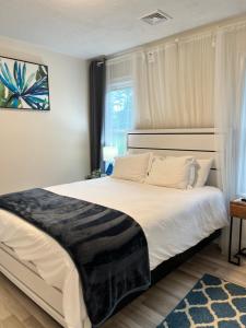 1 dormitorio con 1 cama grande con sábanas blancas y ventana en Private Luxury Framingham condo near Boston, en Framingham