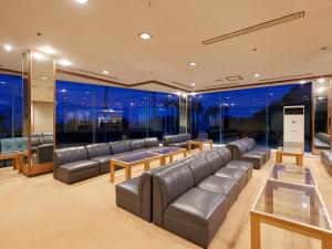 a living room with leather furniture and large windows at Tabist Izu Atagawa Onsen Hotel Gyokuryu in Higashiizu