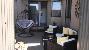 patio con sedie e dondolo sul portico di Angler's Rest a Sunderland Bay