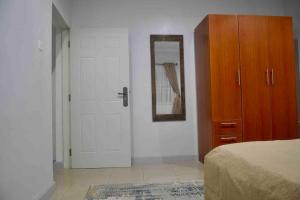 a bedroom with a bed and a dresser and a mirror at Atlantic Court Apartment in Abuja