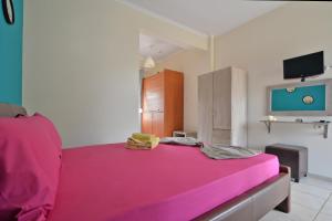 a bedroom with a pink bed with a flat screen tv at Studios Λύδια in Paralía Skotínis