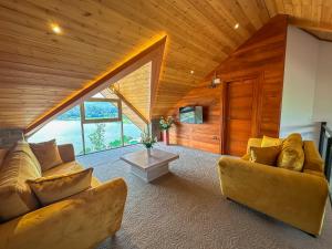 una sala de estar con 2 sofás en una habitación con techos de madera en Baron Luxury Boutique, en Nuwara Eliya