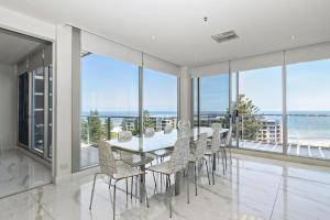 Un comedor con mesa y sillas y el océano. en Belle Escapes - Glenelg Skyline Penthouse, en Glenelg