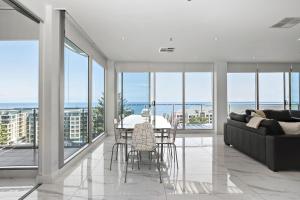 Una sala de estar con un sofá, una mesa y sillas. en Belle Escapes - Glenelg Skyline Penthouse, en Glenelg