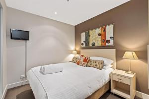 Un dormitorio con una cama y un televisor en la pared. en Belle Escapes - Glenelg Shores Apartment, en Glenelg