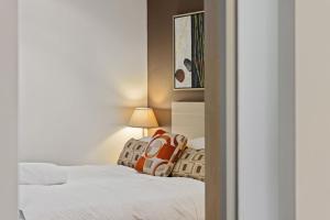 a bedroom with two beds with white sheets and a lamp at Belle Escapes - Glenelg Shores Apartment in Glenelg