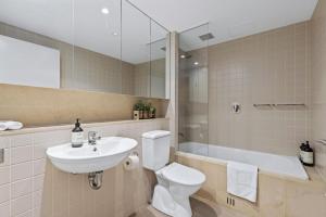 a bathroom with a sink and a toilet and a tub at Belle Escapes - Glenelg Shores Apartment in Glenelg