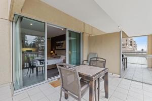 a room with a table and chairs on a balcony at Belle Escapes - Glenelg Shores Studio in Glenelg