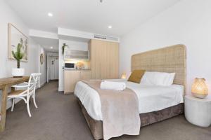 a bedroom with a large bed and a desk at Belle Escapes - Park View Studio at The Pier in Glenelg