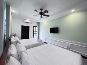 a bedroom with three beds and a ceiling fan at Wanderlust Hotel in Mui Ne