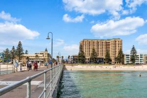 a beach with buildings and people walking on a pier at Belle Escapes - Park View Studio at The Pier in Glenelg