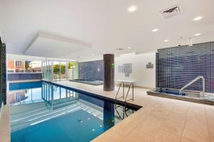 a large swimming pool with blue water in a building at Belle Escapes - Lazy Days on Colley Terrace in Glenelg