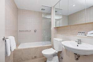 a bathroom with a toilet and a sink and a tub at Belle Escapes - Glenelg Seaside Studio in Glenelg