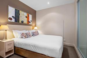 um quarto com uma cama branca e um quadro na parede em Belle Escapes - Glenelg Seaside Apartment em Glenelg
