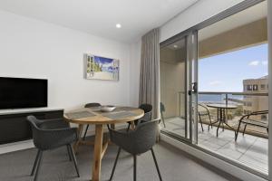 a living room with a table and chairs and a balcony at Belle Escapes - Wine Down at The Pier in Glenelg