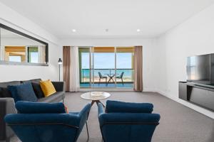 a living room with a couch and chairs and a table at Belle Escapes - Sunset Views at the Bay in Glenelg