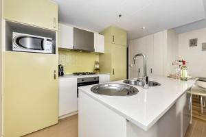 a kitchen with white cabinets and a stainless steel refrigerator at Belle Escapes - Olive Retreat at Glenelg in Glenelg