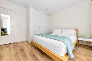 a bedroom with a large bed with a blue blanket on it at Belle Escapes - Olive Retreat at Glenelg in Glenelg