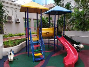 a playground with slides and play equipment in a courtyard at Spacious & Cozy 27FL - 2BR Apartment West Jakarta in Jakarta