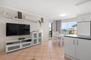 a living room with a flat screen tv and a kitchen at Belle Escapes - Sunny Siesta at Glenelg in Glenelg