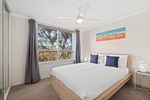 a bedroom with a large bed and a window at Belle Escapes - Sunny Siesta at Glenelg in Glenelg