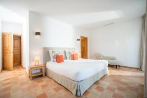 a bedroom with a large white bed and a chair at Relais du vieux sauvaire in Le Lavandou