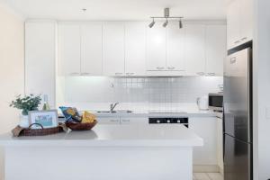 cocina blanca con armarios blancos y nevera en Belle Escapes - Glenelg Oceanview Apartment en Adelaida