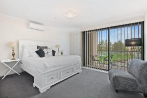 1 dormitorio blanco con 1 cama y 1 silla en Belle Escapes - Glenelg Oceanview Apartment en Adelaida