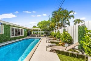 uma piscina com espreguiçadeiras ao lado de uma casa em Delray Beach 4 Bedroom Stylish Pool Home em Delray Beach