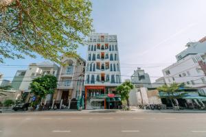 un edificio blanco alto en una calle de la ciudad en La Beaute Hotel Quy Nhơn, en Quy Nhon
