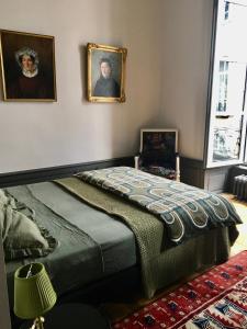um quarto com uma cama e dois retratos na parede em Luxueux 2 pièces 65m2 Hôtel Particulier XVII ième siècle-Centre Historique Clermont-Ferrand em Clermont-Ferrand