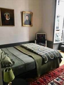 una camera con un letto e due ritratti sul muro di Luxueux 2 pièces 65m2 Hôtel Particulier XVII ième siècle-Centre Historique Clermont-Ferrand a Clermont-Ferrand