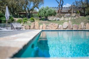 - une piscine avec une chaise et un parasol dans l'établissement Relais du vieux sauvaire, au Lavandou