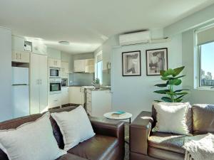 a living room with a leather couch and a kitchen at Quiet location close to it all in Gold Coast