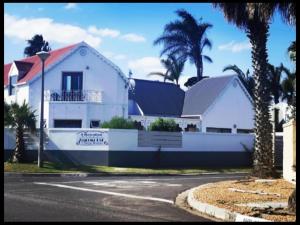 een wit huis met palmbomen voor een straat bij Zagorski bed and breakfast in Kaapstad