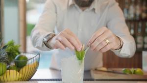 a man in a white shirt stirring a drink at Hôtel Beau Soleil in Le Lavandou