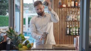 a man standing at a counter in a bar at Hôtel Beau Soleil in Le Lavandou