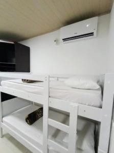 a small white bunk bed with a desk and a bed at suites com cozinha compacta in Cabo Frio