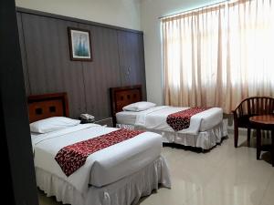 a hotel room with two beds and a table at THE IGNISLO HOTEL SORONG in Sorong