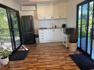 a kitchen with white cabinets and a black refrigerator at Hinchinbrook Riverview Retreat in Upper Stone