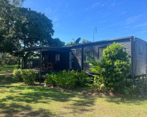 a small house in a yard with trees and grass at Hinchinbrook Riverview Retreat in Upper Stone