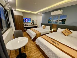 Habitación de hotel con 2 camas y mesa en NEW SKY AIRPORT HOTEL NỘI BÀI, en Noi Bai