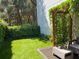 einen kleinen Garten mit einer grünen Wiese und einer Pergola in der Unterkunft Apartament Nadmorski Dwór in Danzig