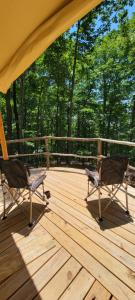two chairs on a wooden deck with trees in the background at Private place for rest in the forest Tent 1 Forrest Cump in Lenoir