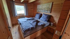 a bed in a wooden cabin with a window at Gemütliches Ferienhaus mit Holzofen und Sauna in Hohentauern