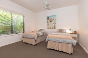 two beds in a white room with a window at At Lizzie in Elizabeth Beach