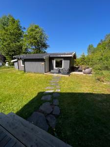 un patio trasero con una casa y un patio de césped en Naturskjønn feriehytte i nærheten av dyreparken, en Kristiansand