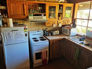 a kitchen with a white stove and a refrigerator at Lyall Street Beach Cabin in Ventnor