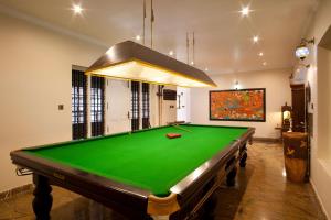 a pool table in a room with a green cloth at StayVista at The Stone Villa with Basketball Court in Kozhikode