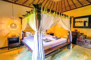una camera da letto con letto a baldacchino con tende di de CINTA Villa - KUTA - 5 bedrooms - Heart of Kuta a Kuta